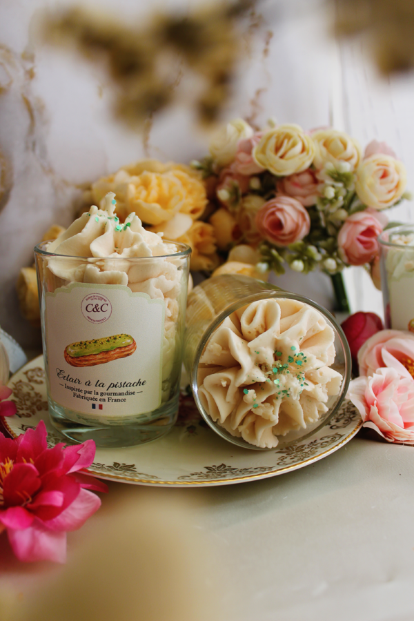 Deux bougies gourmandes Éclair à la pistache de Crèmes et Chantilly, l’une couchée et l’autre debout, avec leur décor de cire façon chantilly.